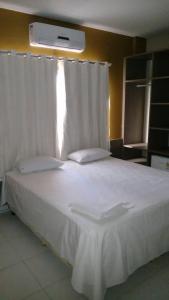 um quarto com uma cama com lençóis brancos e uma janela em Topázio Park Hotel em Afrânio