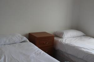 a bedroom with two beds and a wooden night stand at Welltrees Apartments 8 Dailly Road in Maybole