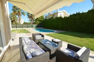 a patio with chairs and a table and a pool at Villa Daryah Sirina Bay in Protaras