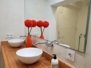 ein Badezimmer mit zwei Waschbecken und zwei Vasen mit roten Blumen in der Unterkunft Moderno y Luminoso Apartamento in Sevilla + 17 Fotos
