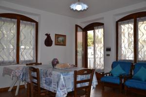 uma sala de jantar com mesa, cadeiras e janelas em Confortevole appartamento a pochi passi dal mare em Cala Gonone