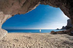a view of a beach with a boat in the ocean at Confortevole appartamento a pochi passi dal mare in Cala Gonone