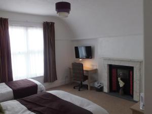 a hotel room with a fireplace and a tv on the wall at Jessamine House Hotel in Gravesend +71 photos
