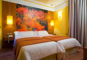 a bedroom with a large bed with a painting on the wall at Suites Gran Vía 44 in Granada