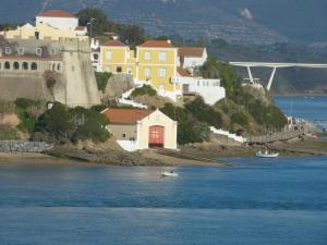 a small boat in the water in front of some buildings at Milfontes Paradise in Vila Nova de Milfontes