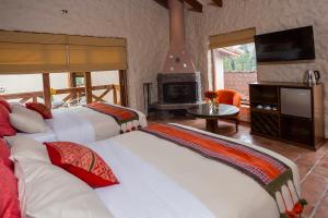 a room with three beds and a fireplace at Intiterra Apart Hotel Villas in Urubamba