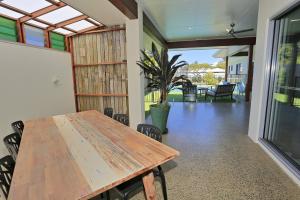 a dining room with a wooden table and a patio at 12th Tee BnB in Bargara