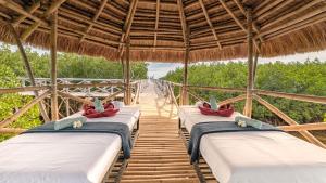 a group of beds in a straw hut with a bridge at North Zen Villas in Panglao Island