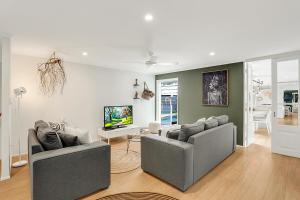 a living room with two couches and a tv at Birdsong in Sunrise Beach