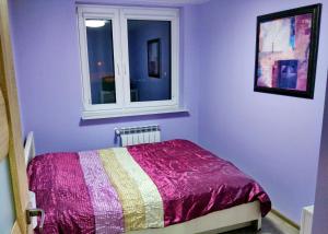 a bedroom with purple walls and a bed with a window at Przytulny Apartament w Gołdapi in Gołdap