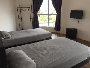 two beds in a room with a window at BENUTHOMESTAY in Johor Bahru
