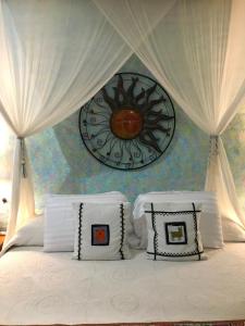 uma cama com almofadas brancas e um relógio na parede em Casa Juanita em Sayulita