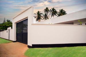 a white house with a black gate and some palm trees at The Ritz Hikkaduwa in Hikkaduwa