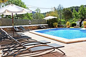 a pool with lounge chairs and an umbrella and a pool at Agroturismo Can Fuster in Sant Joan de Labritja