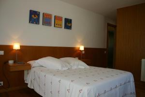 a bedroom with a bed with two lamps on a wall at Casa rural A Mimoseira in A Estrada