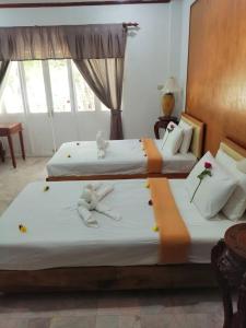 Dos camas en una habitación de hotel con flores. en Tony Home and Restaurant, en Karon Beach