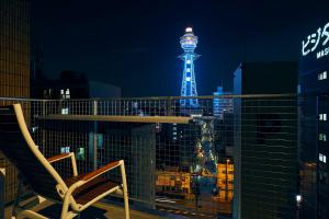 een stoel op een balkon met 's nachts een toren bij Montana Flat Yebisu in Osaka