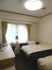 松山市にあるホテル三番町のベッド2台と窓が備わるホテルルームです。