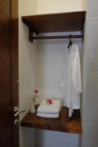 a bathroom with a shelf with towels and a robe at Puri Langenarjan Guest House in Yogyakarta