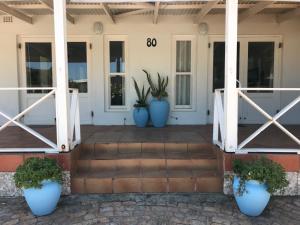 three blue vases sitting on the front porch of a house at Leisure By The Sea in Kleinmond