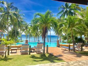 een zwembad met stoelen en palmbomen en de oceaan bij Anda White Beach Resort in Anda