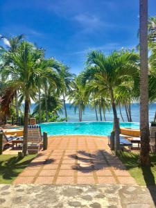 a swimming pool with palm trees and the ocean at Anda White Beach Resort in Anda