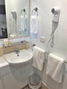 a bathroom with a toilet, sink, mirror and towels at Trinity on Hampden in Perth