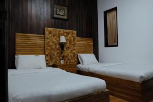 a bedroom with two beds and a lamp on the wall at Puri Minggiran Guest House in Yogyakarta
