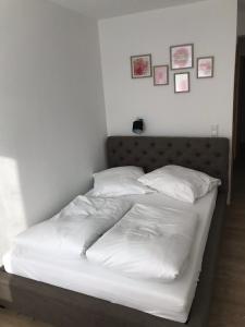 - un lit avec des draps et des oreillers blancs dans une chambre dans l'établissement Gasthof Bräuhäusle, à Baienfurt
