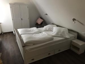 białe łóżko z białą pościelą i poduszkami w obiekcie Gasthof Bräuhäusle w mieście Baienfurt
