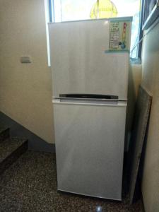 einen weißen Kühlschrank in einem Zimmer mit Treppe in der Unterkunft 酵法自然環保民宿 in Houlong