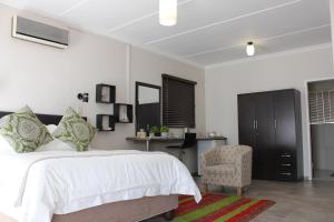 a bedroom with a bed and a chair and a desk at Goedgedacht Guestrooms in Potchefstroom