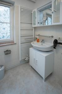 a white bathroom with a sink and a window at Ferienwohnungen Grimma 4 in Grimma