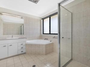 a bathroom with a shower and a tub and a sink at North Entrance Beach House in The Entrance