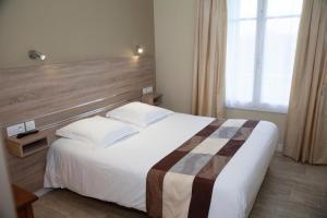 Un dormitorio con una gran cama blanca y una ventana en Hôtel La Pocatière, en Coutances