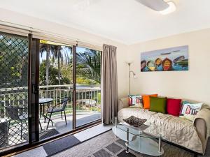a living room with a couch and a balcony at Allamanda 37 in Long Jetty
