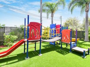 a playground with a slide in a park with palm trees at Allamanda 37 in Long Jetty