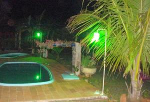 a green street light next to a pool at night at Pousada Recanto Lara in Olímpia