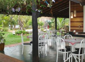 a group of white chairs and tables and a tree at Pousada Recanto Lara in Olímpia
