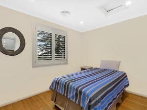 a white bedroom with a bed and a window at Beachfront Luxury in The Entrance