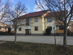 a white house with a red roof and two trees at Orchidea Apartman in Hegykő
