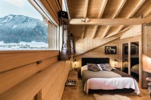 a bedroom with a bed and a large window at Hôtel La Bergerie in Morzine +158 photos