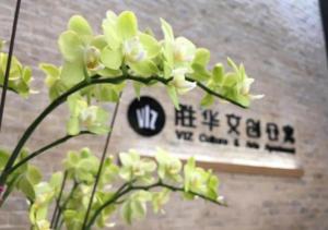 a plant with white flowers in front of a sign at VIZ Culture & Arts Apartment in Nanning