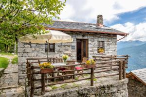 a stone cottage with a table and chairs and an umbrella at Agriturismo Da Attilio in Cannobio