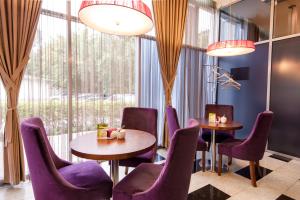 een restaurant met paarse stoelen en tafels en een groot raam bij Grand Avenue by USTA Hotels in Jekaterinaburg