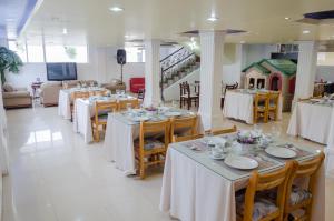 uma sala de jantar com mesas e toalhas de mesa brancas em Hotel El Altar em Riobamba