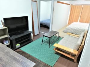 Near Tram Apartment Okayama في أوكاياما: غرفة معيشة مع تلفزيون بشاشة مسطحة وأريكة
