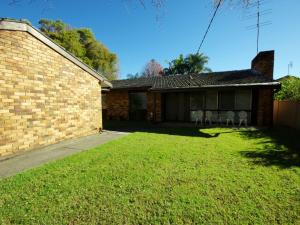 uma casa com duas cadeiras brancas no quintal em Fravent house em Toukley