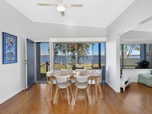 a dining room with a table and chairs at Lake Edge Cottage in Budgewoi
