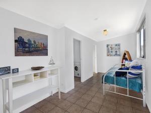 a white room with a bed and a desk at Lake Edge Cottage in Budgewoi